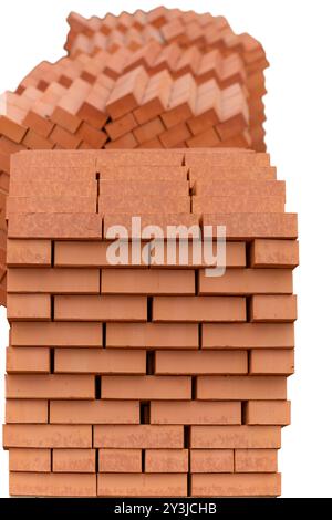 Stapel neuer roter Keramikziegel auf Holzpaletten. Viele neue orange gebaute Ziegelsteine Hintergrund und Textur. Selektiver Fokus. Isoliert am Stockfoto