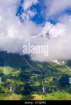 Majestätische hochalpine Berge bedeckt mit grüner Vegetation unter einem hellblauen Sommerhimmel. Wasserbäche, die die Berge hinunter fließen. Großglockne Stockfoto