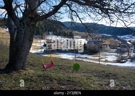 Unter dem Baum hängt eine Kinderschaukel. Skihotels befinden sich in der Ferne. Aktive Wintererholung Stockfoto