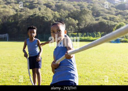 Spielen Sie Tauziehen, multirassische Jungen auf dem Schulsportplatz und genießen Sie Outdoor-Aktivitäten Stockfoto
