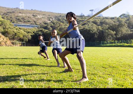 Drei multirassische Jungs spielen Tauziehen und auf dem Schulfeld Outdoor-Aktivitäten genießen Stockfoto