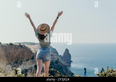 Frau in einem Hut, die die Aussicht von einer Klippe aus bewundert Stockfoto