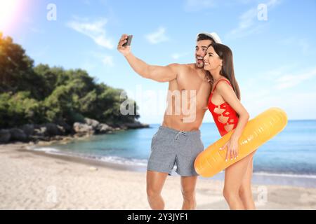 Glückliches Brautpaar, das in den Flitterwochen Selfie auf See macht. Ein Paar lächelt am tropischen Strand während des sonnigen Tages Stockfoto