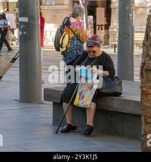 Jerusalem, Israel - 18. Juli 2024: Eine ältere Frau, die auf einer Bank im Zentrum Jerusalems sitzt und in ihre Handtasche schaut. Stockfoto