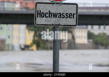 Passau, Deutschland. September 2024. Am Ufer des Inn steht ein Schild mit der Aufschrift "Hochwasser". Auch wenn der meiste Regen am Wochenende in Bayern wahrscheinlich schon gefallen ist, wird sich der Niederschlag erst Stunden oder Tage später an den Flüssen bemerkbar machen. In Passau, wo drei Flüsse aufeinander treffen, sollte nach Angaben der Stadt in den Abendstunden mit den ersten Schließungen in der Altstadt gerechnet werden. Quelle: Armin Weigel/dpa/Alamy Live News Stockfoto