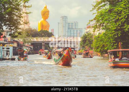 Blick auf die große Buddha-Statue in Bangkok, Thailand (Wat Pak Nam Phasi Charoen) vom Kanal aus mit Holzhäusern und Langschwanzbooten Stockfoto