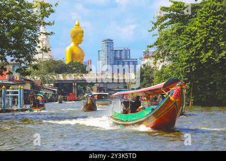 Blick auf die große Buddha-Statue in Bangkok, Thailand (Wat Pak Nam Phasi Charoen) vom Kanal aus mit Holzhäusern und Langschwanzbooten Stockfoto