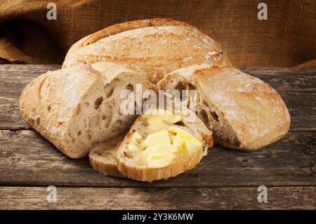 Studio-Aufnahme von Butter, die auf Sauerteigbrotscheiben schmilzt, die auf einem dunklen Holzhintergrund ruhen - John Gollop Stockfoto