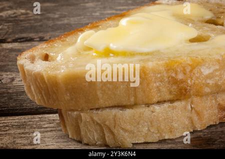 Studio-Aufnahme von Butter, die auf Sauerteigbrotscheiben schmilzt, die auf einem dunklen Holzhintergrund ruhen - John Gollop Stockfoto