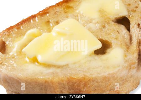 Studio-Aufnahme von Butter, die auf Scheiben Sauerteigbrot schmilzt, die vor weißem Hintergrund ausgeschnitten wurden - John Gollop Stockfoto