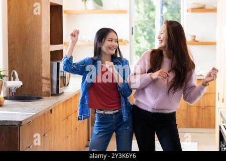 Zu Hause tanzen zusammen, asiatische Mutter und Tochter genießen Zeit in der modernen Küche Stockfoto