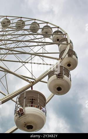 Nahaufnahme eines Riesenrads mit mehreren Fahrerkabinen vor einem bewölkten Himmel. Die Konstruktion ist metallisch und zeigt das komplizierte Design von Th Stockfoto