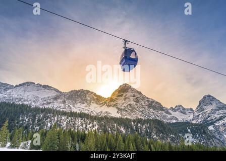 Seilbahn Route über die österreichischen Alpen Berge mit ihren Tannenwälder, während die Sonne hinter den Gipfeln. Bild in Ehrwald Austr genommen Stockfoto