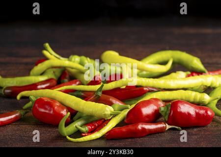 Eine Mischung aus grünem und rotem Paprika liegt auf einer dunklen Holzoberfläche, Lebensmittelfotografie Stockfoto