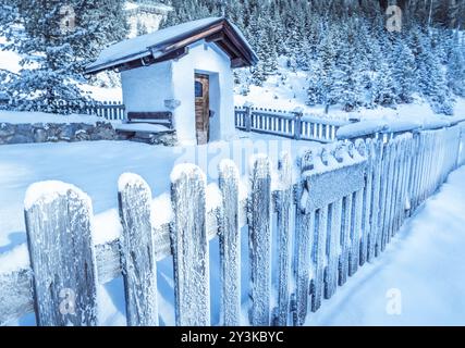 Idyllische Winterlandschaft mit einem alten, schneebedeckten Holzzaun, der eine urige Bergkapelle umgibt, in den österreichischen Alpen. Bild aufgenommen in Ehrwald Stockfoto