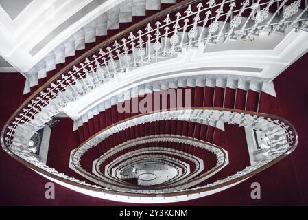 Architektonische Symmetrie mit eleganten Wendeltreppen, über dem Blick, aus weißem Marmor und mit rotem Teppich bedeckt, in einem Hotel in Genua, Italien, Europa Stockfoto