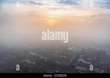 Farbenfroher Wintersonnenuntergang durch den Nebel über der Stadt Ljubljana, der Hauptstadt Sloweniens, an einem kalten Dezembertag aus der Vogelperspektive Stockfoto