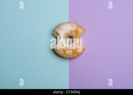 Köstliche Krapfen, von zwei Standorten gebissen, blau und violett gefärbten Hintergrund. Flach Bild Stockfoto