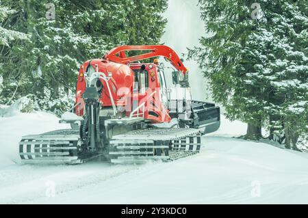 Verfolgt pistenfahrzeug an einem verschneiten Straße, durch den Wald, in den österreichischen Alpen, in Reutte Bezirk Stockfoto