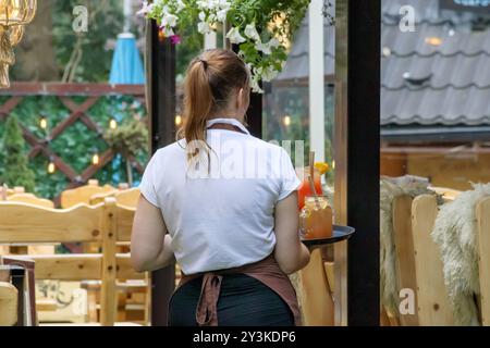 Eine Frau bedient Kunden in einem Sommer-Café im Freien Stockfoto