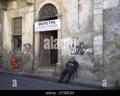 NIKOSIA, ZYPERN, 17. März 2018: Ein Sargmacher, der vor seiner Werkstatt in einem alten zerbröckelnden Gebäude in der Altstadt von Nikosia auf zypern ruht. Der Text Stockfoto