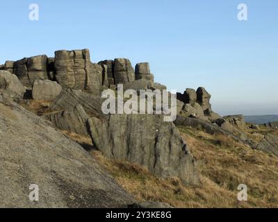 Großer, zerklüfteter Gritsteinaufschluss an den Bridestonen einer großen Felsformation in West yorkshire bei todmorden mit blauem sonnendurchflutetem Himmel Stockfoto