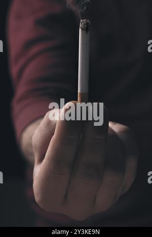 Des Menschen Hand mit einer brennenden Zigarre, eine Nahaufnahme Bild bei wenig Licht. Quit Smoking Konzept Stockfoto