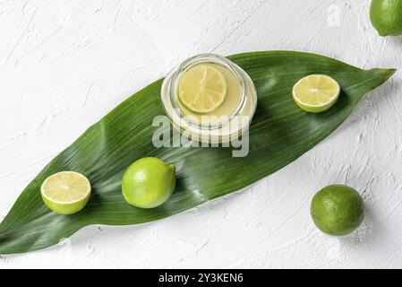 Frische Limonade in einem Glas und grünem Limes auf ein Blatt. Oben Ansicht mit einer weißen Küche Tisch und Stockfoto