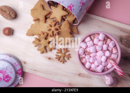 Weihnachtsbonbons mit einer Tasse heißem Kakao mit rosafarbenen Mini-Marshmallows, einer umgedrehten Schachtel mit Lebkuchenkeksen auf einer Holzplatte Stockfoto