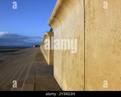 Perspektivischer Blick auf die Betonmauer in blackpool mit Stufen, die in warmer Nachmittagssonne mit blauem bewölktem Himmel zum Strand führen Stockfoto