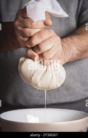 Mann bereitet Horchata durch Quetschen Milch aus Mandel und Reis Mischung in einer Schüssel. Vegane Milch nach Hause Zubereitung. Herstellung von Horchata, Sommer mexikanischen Getränk Stockfoto