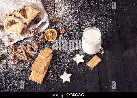 Winter Frühstück mit Gebäck, Lebkuchen cookies, Walnüsse, Mandeln und eine Tasse Milch auf einem Holztisch und Pound Cake auf einem Küchenpapier Stockfoto