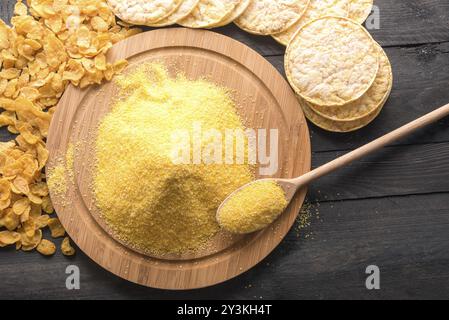 Hohe Betrachtungswinkel und einer runden Platte voller Mais Mehl, durch Produkte aus it, Corn Flakes und Gepuffter mais Kuchen umgeben, auf einem schwarzen Holz- ta Stockfoto