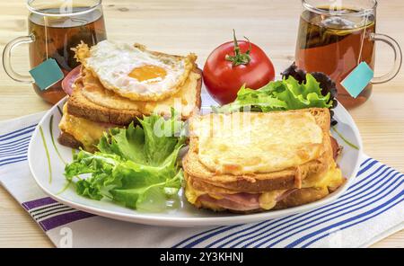 Leckeres Frühstück für zwei Personen mit speziellen französischen Speisen, Croque Madame (mit Ei) und Croque Monsieur, gewürzt mit frischem Salat und Tee Stockfoto