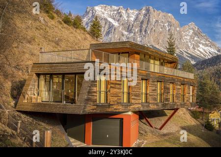 Alpine Landschaft mit einem Berggipfel im Hintergrund und im Vordergrund ein interessantes modernes Gebäude, ein hängendes Holzhaus Stockfoto