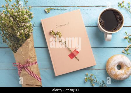 Kaffeetasse mit einem donut als Frühstück auf Blau Holztisch und Frühling Blumen Blumenstrauß in der Nähe der rosa Journal Stockfoto