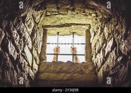 Mann außerhalb des Gefängnisses mit seinen Händen die Metallstangen aus dem Fenster Stockfoto