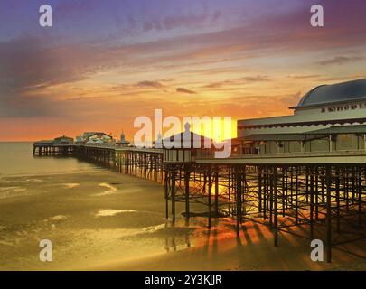 Der Sonnenuntergang über dem historischen North Pier in blackpool mit leuchtendem goldenem Licht, das am Strand reflektiert wird, und der farbenfrohe Himmel in der Dämmerung Stockfoto