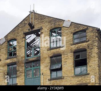 Das kaputte Dach und die kaputten Fenster in einem großen, verbrannten alten Industriehaus nach einem Brand Stockfoto