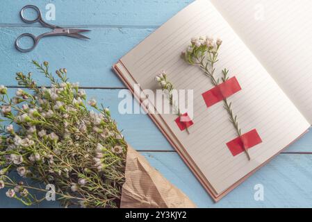 Weiße Blumen auf der Tagesordnung Seiten angefügt und ein Blumen Blumenstrauß auf einem blauen Holztisch, flach Bild Stockfoto