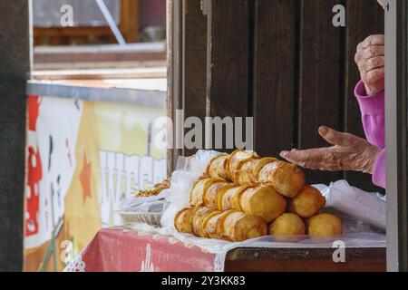 Stücke von geräuchertem Käse auf der Theke mit den Händen der alten Tante im Hintergrund Stockfoto