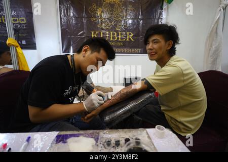 Lalitpur, Nepal. September 2024. Ein Künstler (L) färbt ein Tattoo auf den Körper eines Enthusiasten (R) während der Himalaya Tattoo Convention in Lalitpur, Nepal, am 14. August 2024. Der von der National Academy of Fine Arts und der Nepal Handicraft Association unterstützte Tattoo Summit zeigt mehr als vier Dutzend Künstler, die Götterbilder mit modernen Konzepten einfärben. (Foto: Subaas Shrestha/NurPhoto) Credit: NurPhoto SRL/Alamy Live News Stockfoto