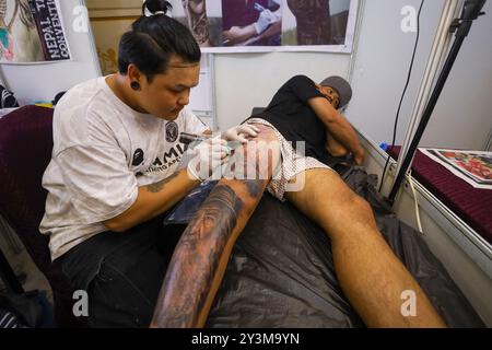 Lalitpur, Nepal. September 2024. Ein Künstler (L) färbt ein Tattoo auf den Körper eines Enthusiasten (R) während der Himalaya Tattoo Convention in Lalitpur, Nepal, am 14. August 2024. Der von der National Academy of Fine Arts und der Nepal Handicraft Association unterstützte Tattoo Summit zeigt mehr als vier Dutzend Künstler, die Götterbilder mit modernen Konzepten einfärben. (Foto: Subaas Shrestha/NurPhoto) Credit: NurPhoto SRL/Alamy Live News Stockfoto