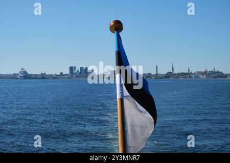 Estnische Flagge winkt vor dem Hafen von Tallinn, der Altstadt, der Skyline und der Ostsee, vom Boot aus gesehen. Markierung im Fokus. Stockfoto