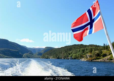 Die norwegische Flagge winkt mit dem Secenischen Fjord im Hintergrund. Fährfahrt von Gudvangen nach Flam auf Norwegen in einer Nutschalen Tour Stockfoto