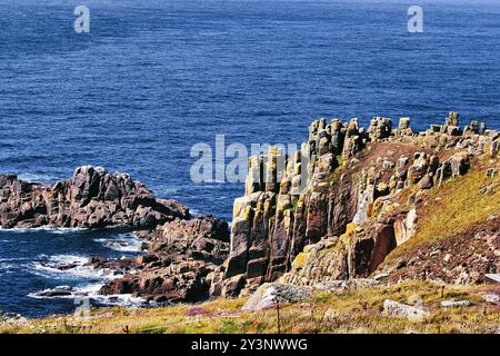 Ein malerischer Blick auf die Küste mit zerklüfteten Klippen und Felsformationen, die mit Moos und Flechten bedeckt sind, mit Blick auf das tiefblaue Meer. Die Landschaft ist gepunktet Stockfoto