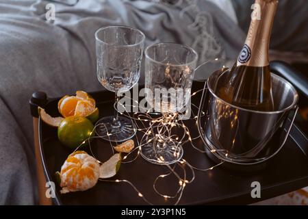 Ein Tablett mit einer Flasche Champagner, zwei Weingläsern und Obst. Die Szene ist feierlich und festlich. Stockfoto