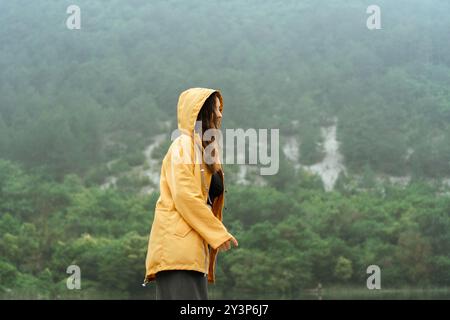 Eine Frau in einer gelben Jacke steht in einem Wald Stockfoto