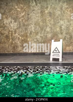 Vertikales Foto des Warnhinweises „Wet Floor“ im modernen Spa neben dem Jacuzzi-Pool, Kopierraum. Stockfoto