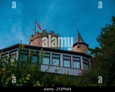 Ein Schuss von einer Burg mit einer Fensterfront und einem alten Turm mit einer Flagge darüber Stockfoto